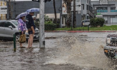 Una pareja sale de compras por una calle inundada en la ciudad de Tijuana (México). EFE/Joebeth Terriquez