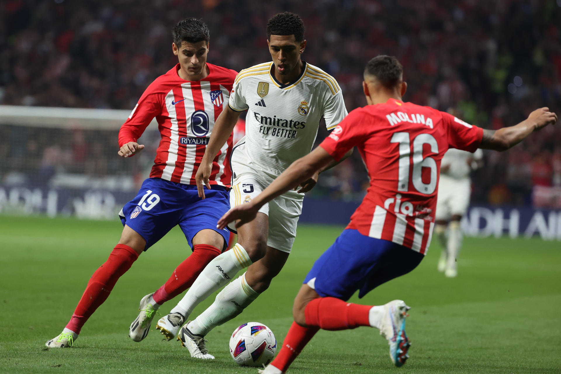 El delantero del Atlético de Madrid Álvaro Morata (i) y el defensa argentino Nahuel Molina disputan un balón ante el centrocampista británico Jude Bellingham (c) Real Madrid durante el partido de la sexta jornada de LaLiga. EFE/ Kiko Huesca