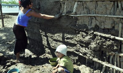 Fotografía de archivo de un niño y una joven que ayudan a construir una pared de lodo. EFE/Gustavo Amador