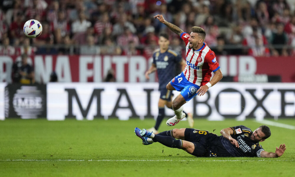 El centrocampista del Girona Cristian Portugués "Portu" (encima) sufre la entrada del defensa del Real Madrid Nacho Fernández durante el partido de la jornada 8 de Liga de Primera división en el estadio de Montilivi, en Girona. EFE/Siu Wu