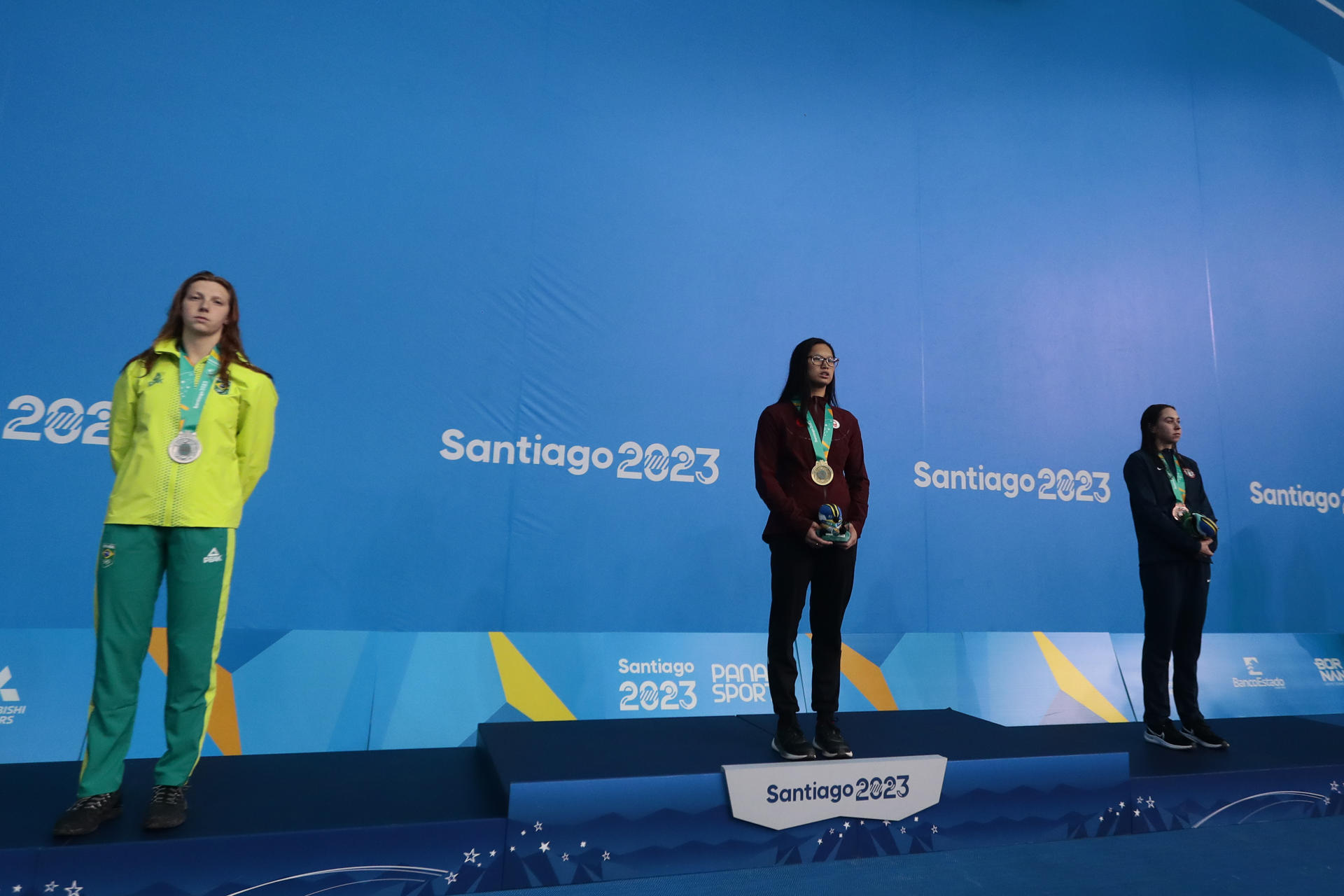 Maggie Mac Neil (c) de Canadá, medalla de oro; Stephanie Balduccini (i) de Brasil, medalla de plata; y Catie DeLoof de Estados Unidos, bronce, posan en el podio de 100m libre hoy, en la natación de los Juegos Panamericanos 2023, en Santiago (Chile). EFE/Osvaldo Villarroel
