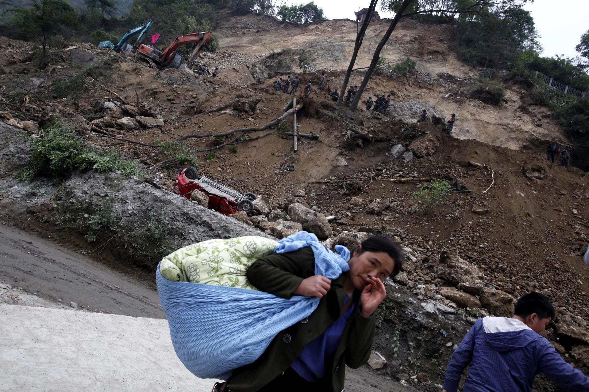 Una mujer china fue registrada este jueves, 21 de diciembre, al cargar sus pertenencias cerca de una zona afectada por el terremoto de magnitud 6,2 que el pasado 18 de diciembre azoto el condado de Baoxin (China). EFE/Wu Hong