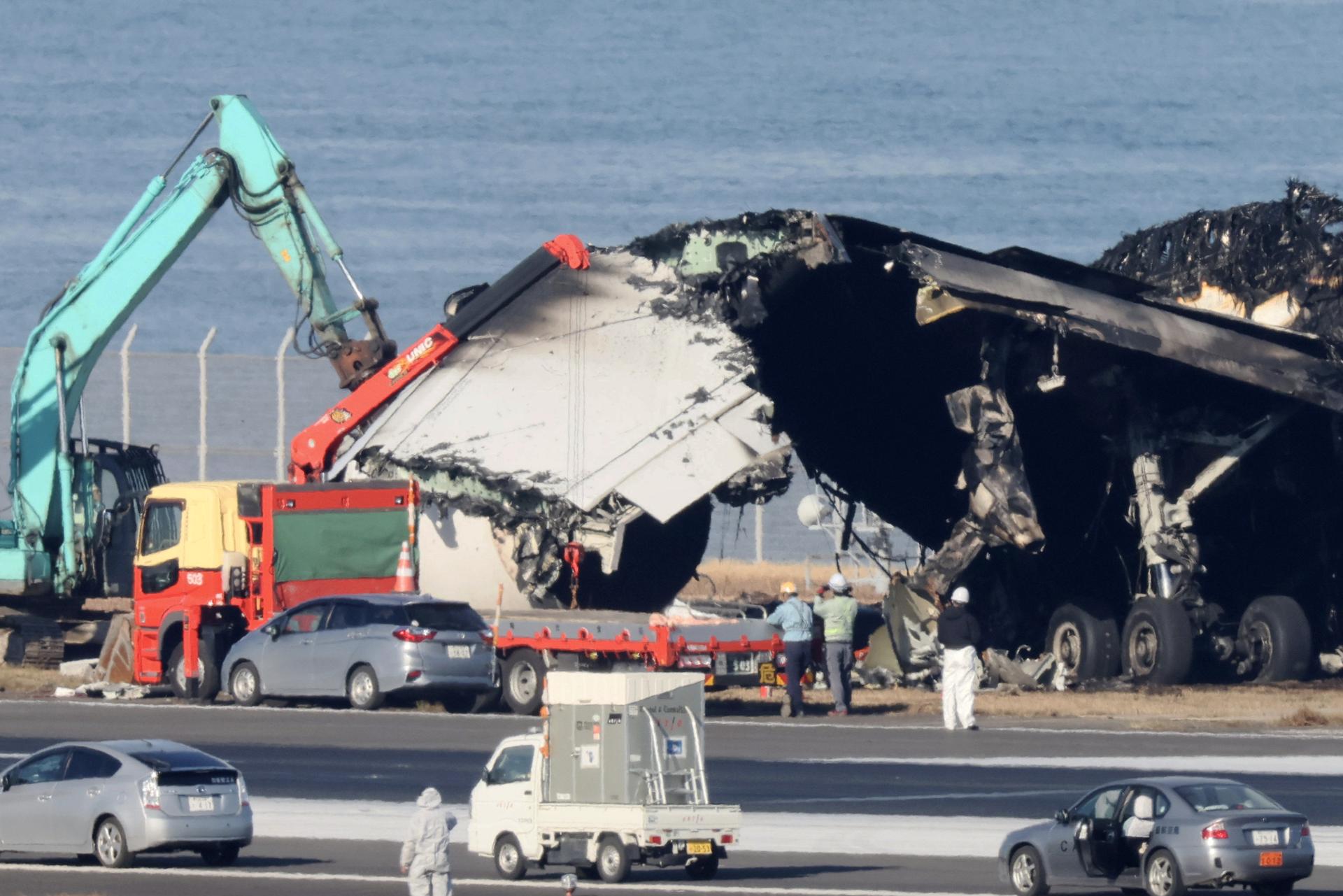 Trabajadores retiran los restos del accidente de un avión de pasajeros de Japan Airlines con un avión de la Guardia Costera nipona en el aeropuerto tokiota de Haneda, en Tokio (Japón), el 5 de enero de 2024. EFE/EPA/Jiji Press