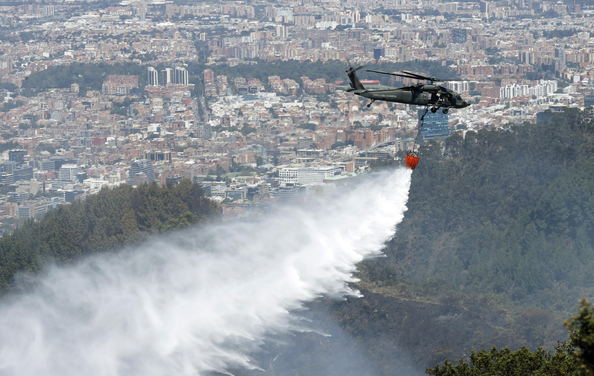 AME1624. BOGOTÁ (COLOMBIA), 23/01/2024.- Un helicóptero de la Fuerza Aérea Colombiana (FAC) participa hoy en labores de extinción de los incendios en los cerros orientales de Bogotá (Colombia). El incendio que comenzó ayer en los cerros orientales de Bogotá sigue activo y se ha extendido afectando a aproximadamente cuatro hectáreas de bosques en las últimas horas, aunque los bomberos aseguran que ya está "en control". EFE/ Mauricio Dueñas Castañeda