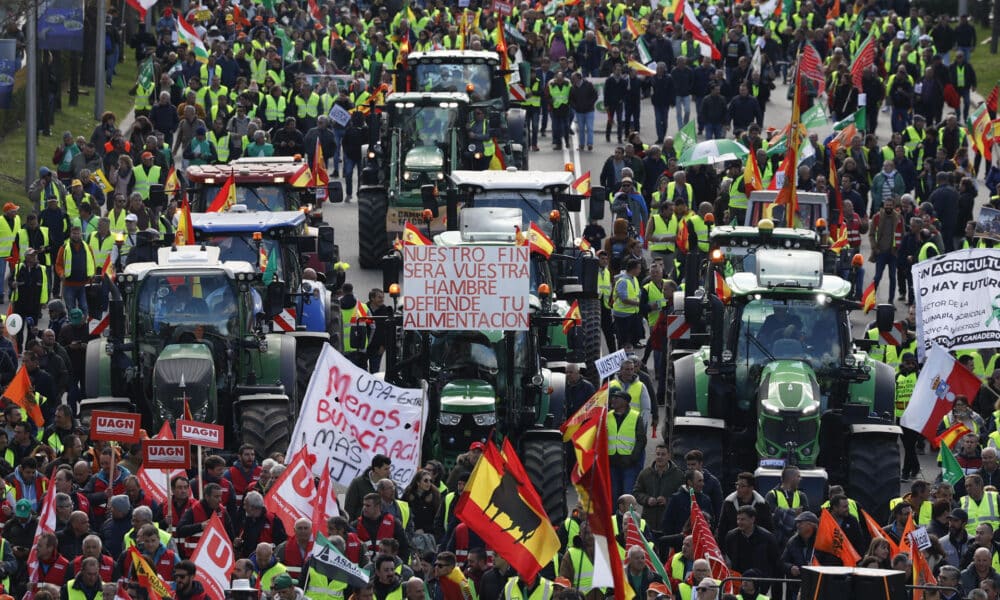 Tractores y personas a pie de la protesta agrícola convocada este lunes en la ciudad de Madrid que ha llegado hasta el Ministerio de Agricultura, Pesca y Alimentación, ya en la capital, tras salir a primera hora de la mañana del municipio de Arganda del Rey, en un recorrido que, hasta el momento, se ha desarrollado con "normalidad". EFE/  JJ.Guillén