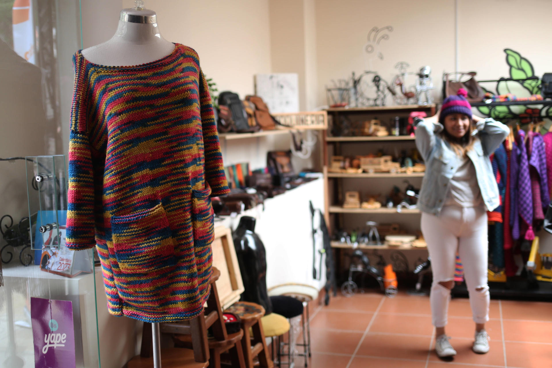 Una mujer probándose una prenda es vista al interior de una tienda que ofrece ropa confeccionada por internas de centros penitenciarios, el 6 de febrero de 2024, en La Paz (Bolivia). EFE/Luis Gandarillas