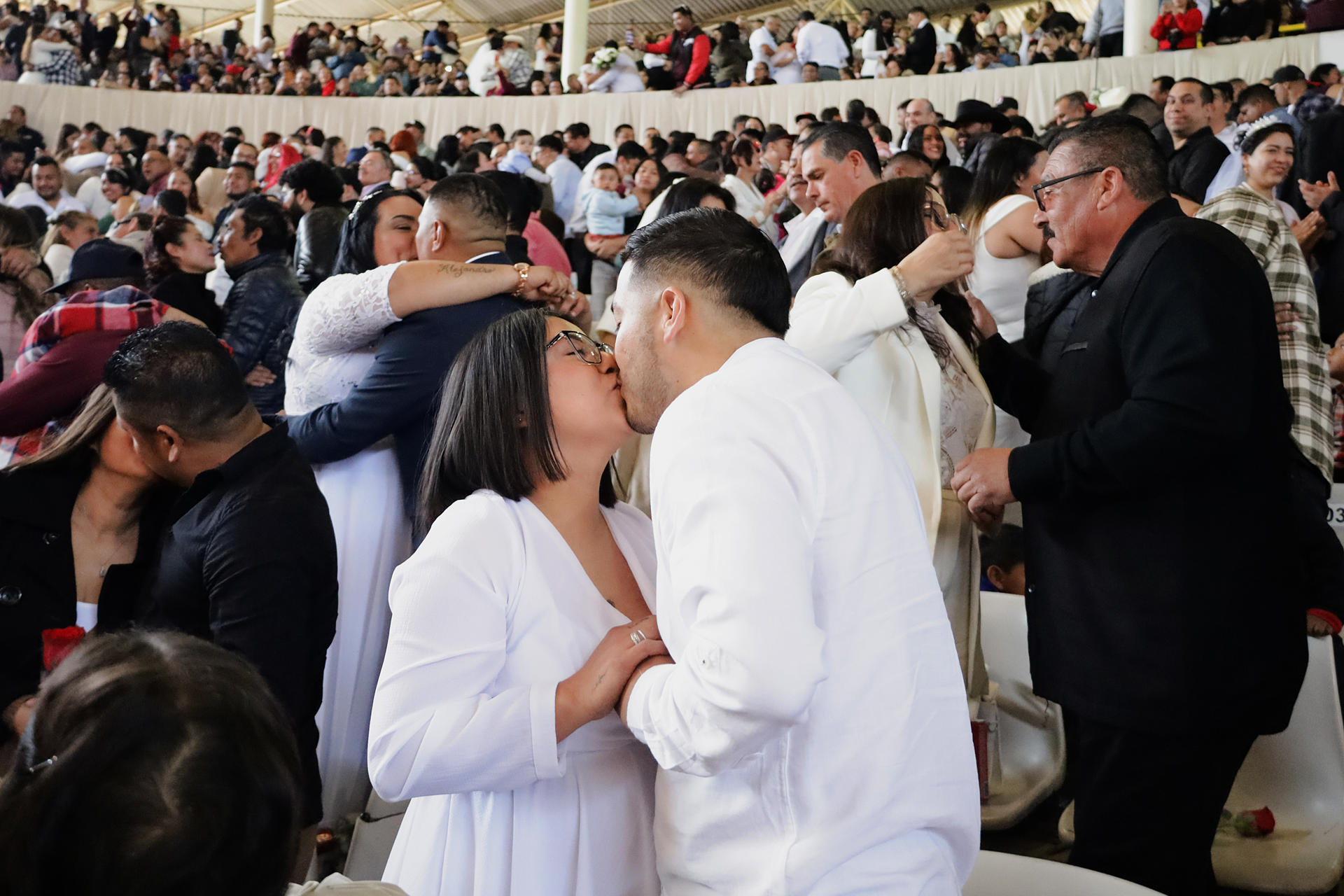 Parejas se besan al contraen matrimonio este miércoles durante una boda colectiva en la ciudad de Tijuana, Baja California (México). EFE/Joebeth Terriquez