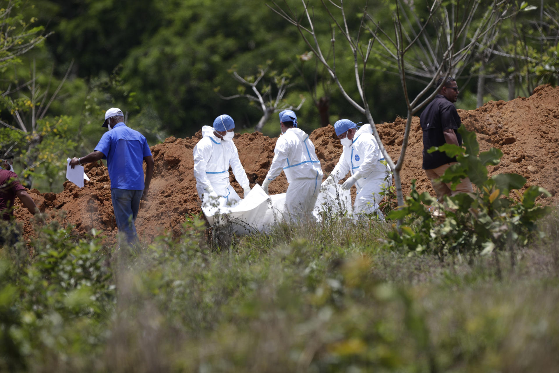Fotografía de archivo de trabajadores forenses mientras entierran los cuerpos de migrantes fallecidos durante un accidente en autobús el año pasado en el mes de febrero, en David (Panamá). EFE/ Bienvenido Velasco