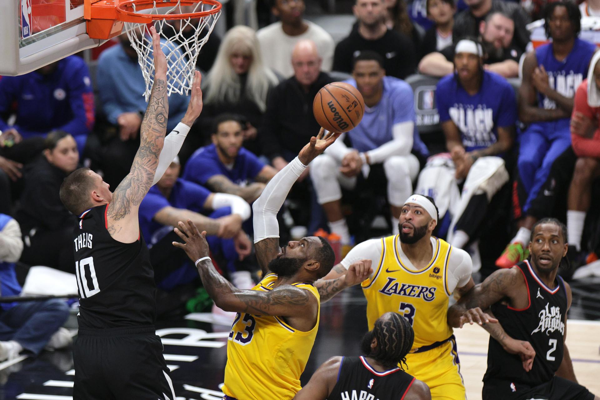 El jugador de los Angeles Lakers LeBron James (2-I) lanza la pelota a canasta con la oposición del jugador de los Angeles Clippers Daniel Theis (i) durante la segunda mitad del partido de baloncesto de la NBA entre los Angeles Lakers y Los Angeles Clippers en Los Ángeles, California, EE. UU. EFE/EPA/ALLISON DINNER