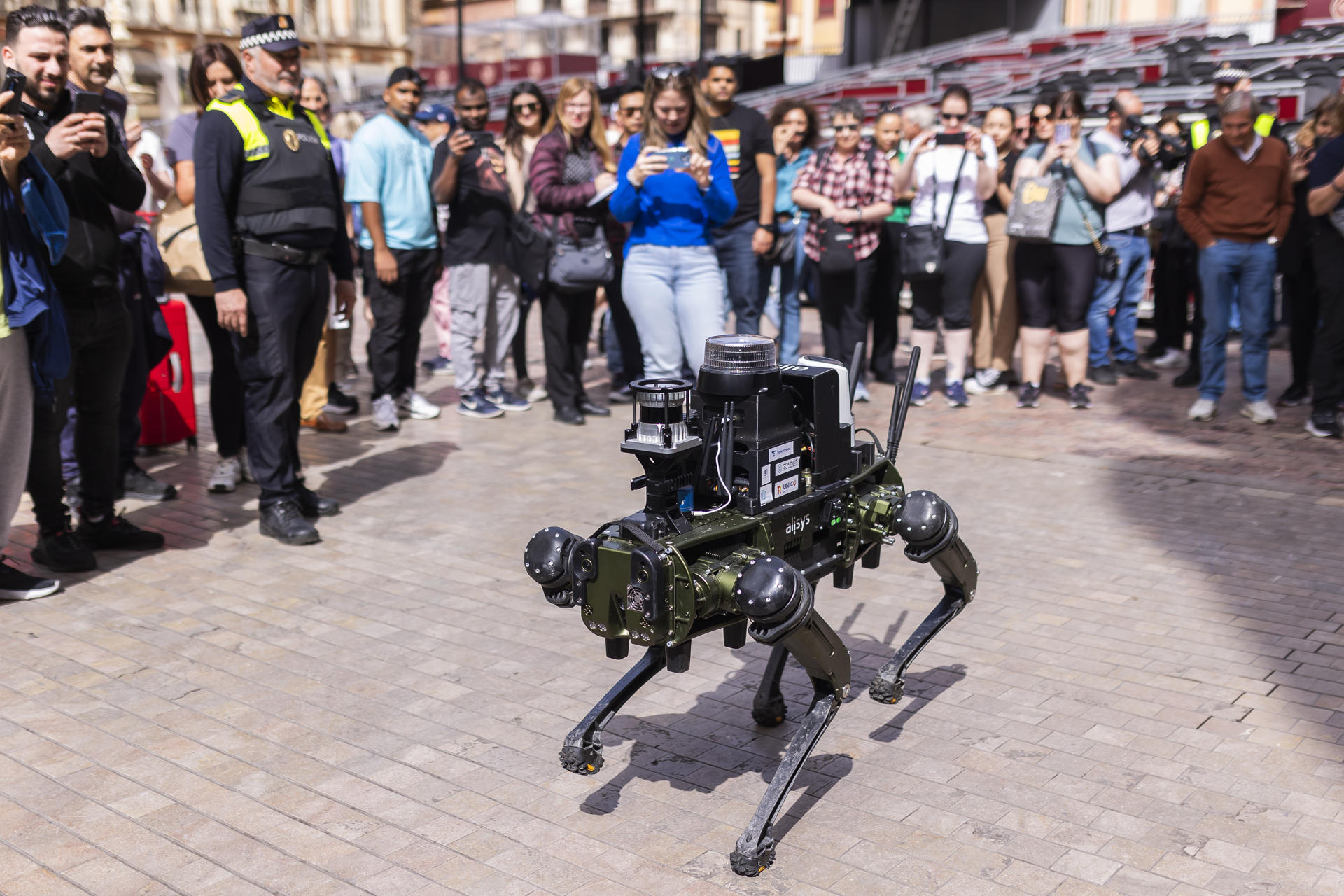 Agentes de la Policía Local de Málaga realizan una demostración práctica este martes en la calle Marqués de Larios de la capital malagueña de un robots cuadrúpedo que ha diseñado la Universidad (UMA) y que puede patrullar con los municipales. EFE/Carlos Díaz