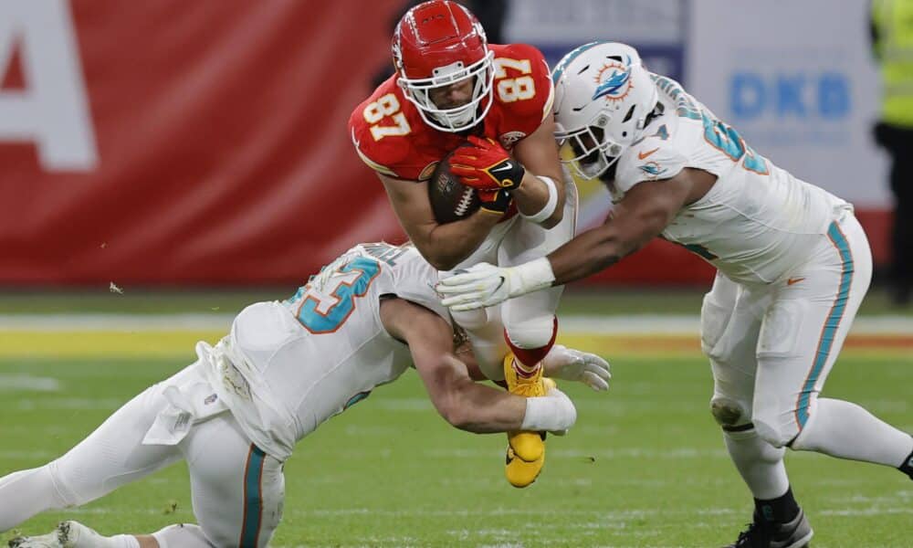 Fotografía de archivo en donde se observa a Travis Kelce (c) de los Kansas City Chiefs siendo abordado por el linebacker de los Miami Dolphins Andrew Van Ginkel (i) y el tackle defensivo de los Miami Dolphins Christian Wilkins (d) durante un juego de la NFL. EFE/EPA/RONALD WITTEK