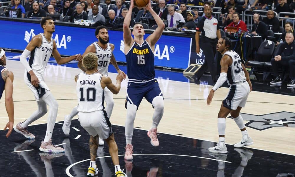 El serbio Nikola Jokic (c), pívot estrella de los Nuggets de Denver, fue registrado este viernes, 15 de marzo, al atacar el aro que defienden los Spurs de San Antonio, durante un partido de la NBA, en Austin (Texas, EE.UU.). EFE/Adam Davis