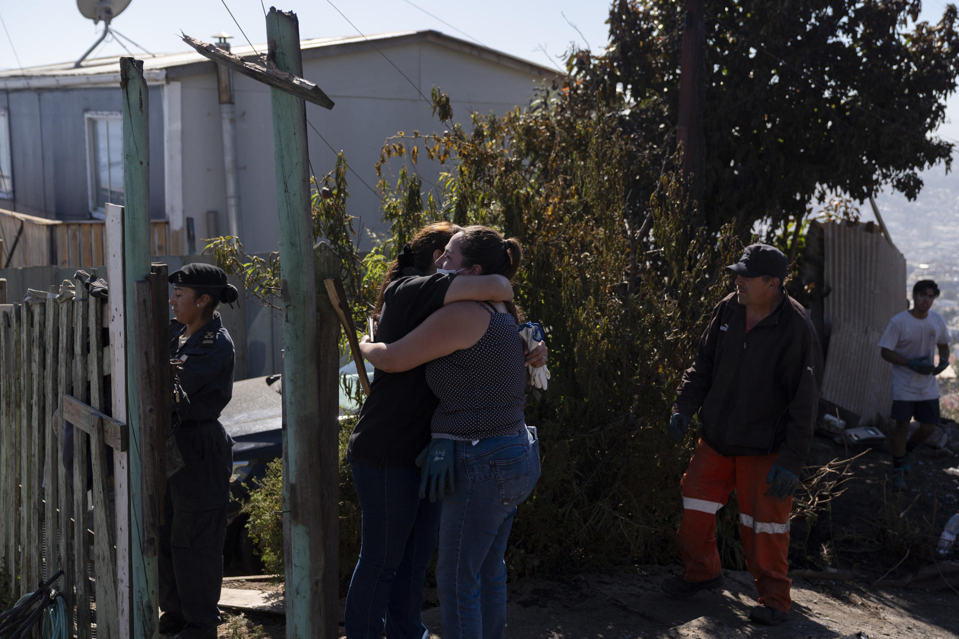 Personas se abrazan este jueves tras el incendio que afectó la noche del miércoles 13 de marzo al Cerro Cordillera en Valparaíso (Chile). EFE/Adriana Thomasa