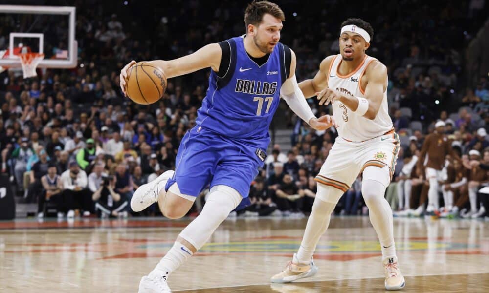 El esloveno Luka Doncic (c), escolta estrella de los Mavericks de Dallas, fue registrado este martes, 19 de marzo, al intentar superar la marca de Keldon Johnson (d), de los Spurs de San Antonio, durante un partido de la NBA, en San Antonio (Texas, EE.UU.). EFE/Adam Davis