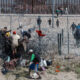 Migrantes cruzan una alambrada de navajas y púas, en la frontera que divide a México de los Estados Unidos en Ciudad Juárez (México). Fotografía de archivo. EFE/Luis Torres