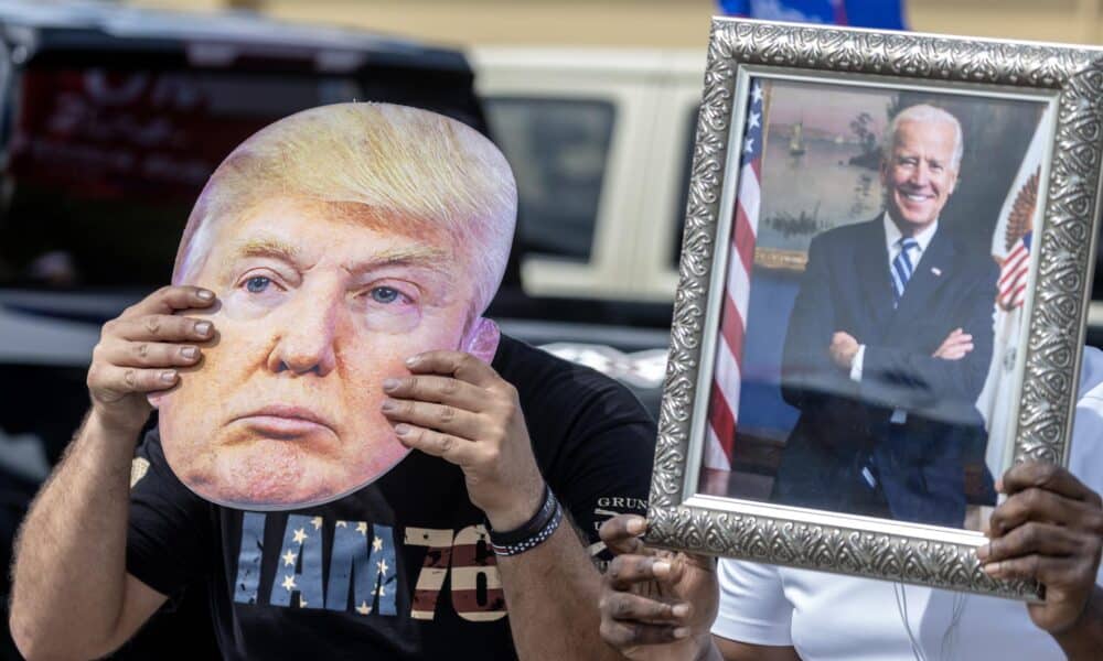 Fotografía de archivo donde se aprecia dos personas con un retrato de Biden y una máscara de Trump. EFE/EPA/CRISTOBAL HERRERA-ULASHKEVICH