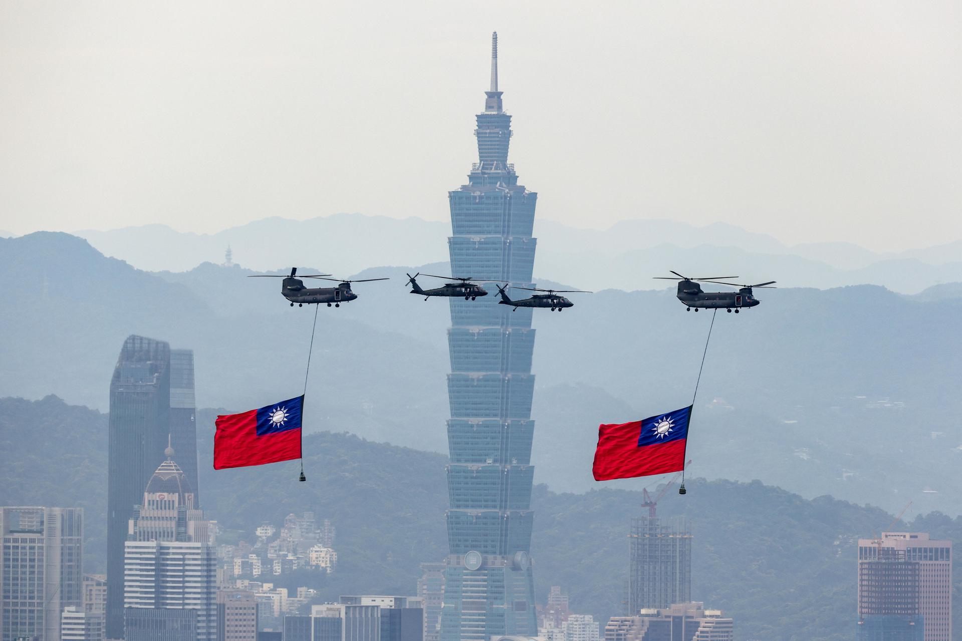 Helicópteros de la Fuerza Aérea de Taiwán llevan banderas nacionales mientras realizan un sobrevuelo durante un ensayo antes de la toma de posesión del presidente electo William Lai en Taipei, Taiwán. EFE/EPA/Ritchie B. Tongo