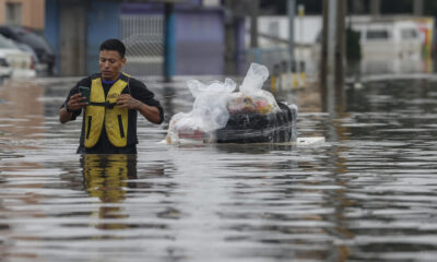 Un hombre transporta suministros en una tabla en medio de una calle inundada en el barrio de Humaita en Porto Alegre (Brasil). EFE/Sebastião Moreira