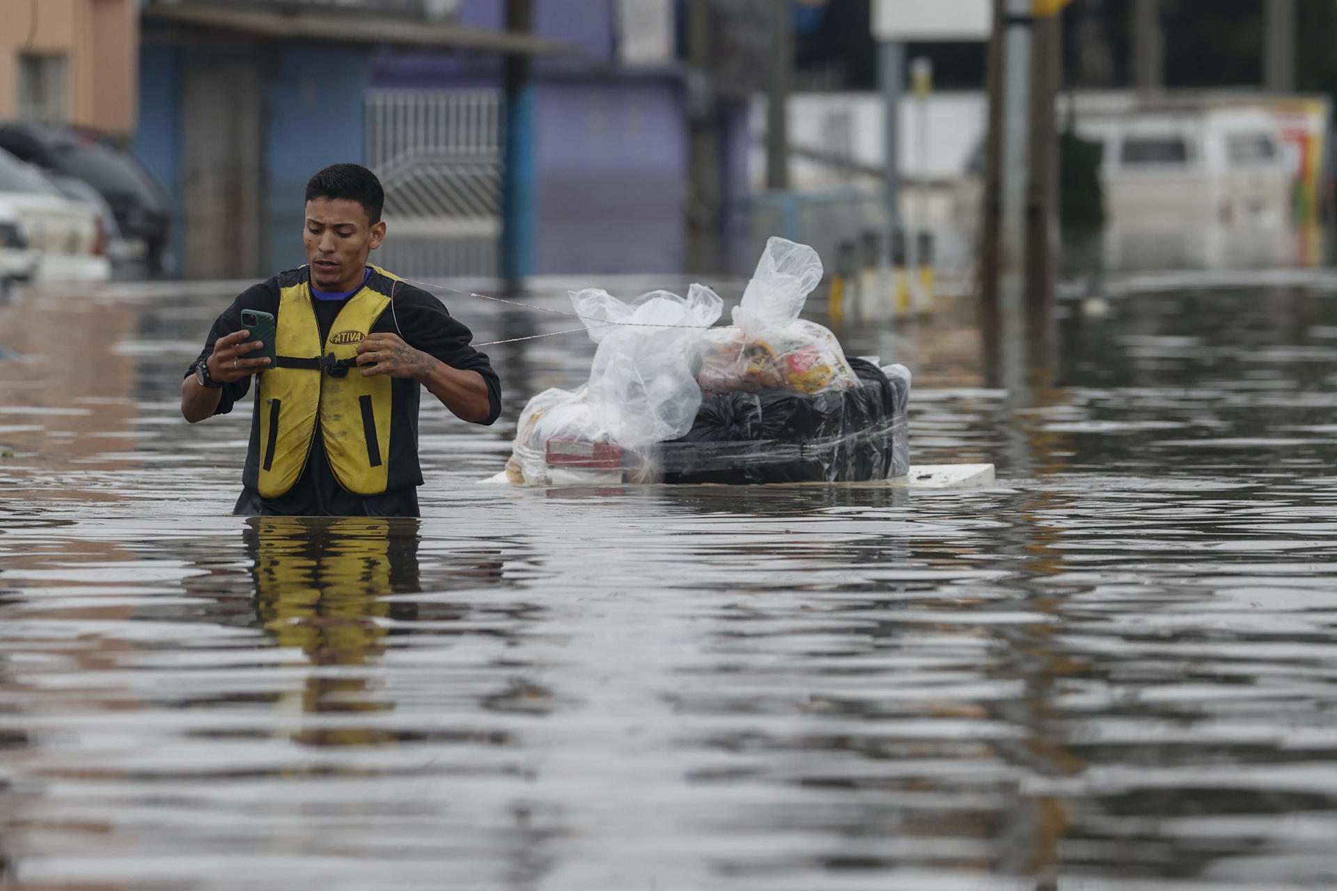 Un hombre transporta suministros en una tabla en medio de una calle inundada en el barrio de Humaita en Porto Alegre (Brasil). EFE/Sebastião Moreira