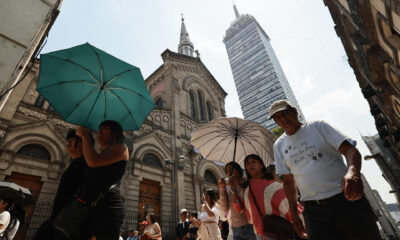 Varias personas caminan con sombrilla para protegerse del sol, este viernes en Ciudad de México (México). EFE/José Méndez