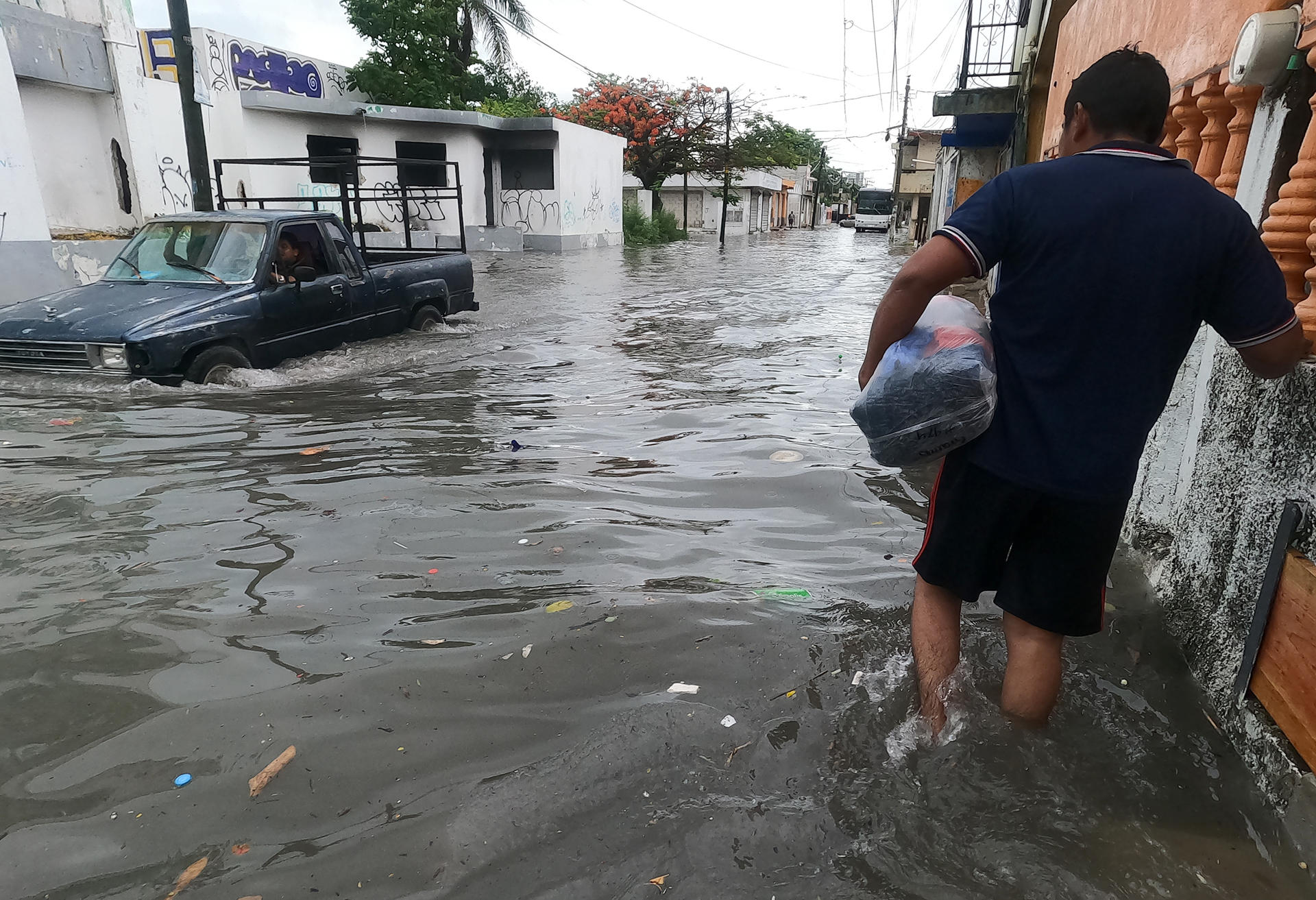 Un hombre y vehículo circulan por una calle inundada debido a las fuertes lluvias en Cancún, estado de Quintana Roo (México). EFE/ Alonso Cupul