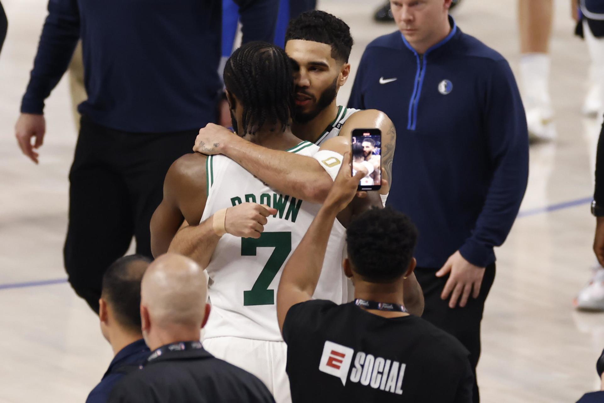 Jayson Tatum (c-d), alero estrella de los Celtics de Boston, fue registrado este miércoles, 12 de junio, al abrazar a su compañero Jaylen Brown (c-i), al final del tercer partido de las Finales de la NBA, en el que vencieron 99-106 a los Mavericks de Dallas, en el coliseo American Airlines Center de Dallas (Texas, EE.UU.). EFE/Adam Davis