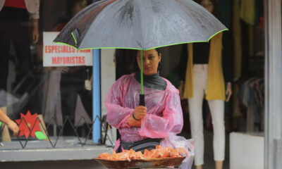Una muer se protege de la lluvia mientras vende frutas, este lunes en Tegucigalpa (Honduras). EFE/ Gustavo Amador