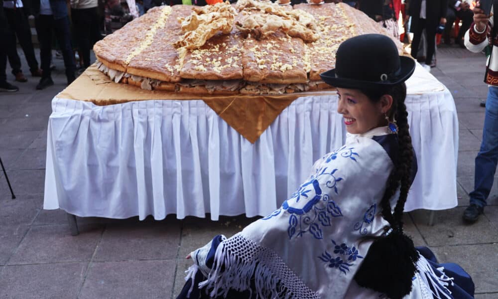 Una mujer aimara posa junto al Sándwich de chola más grande del mundo, este martes en La Paz (Bolivia). EFE/ Luis Gandarillas