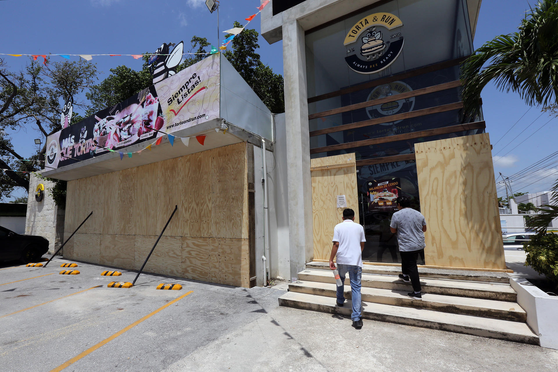 Trabajadores colocan tablas de madera para proteger un establecimiento por el paso del huracán Beryl, este miércoles en Cancún (México). EFE/Alonso Cupul