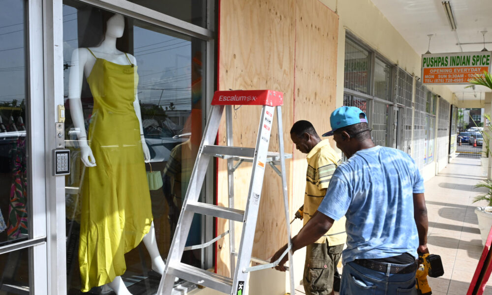 Personas cubren las fachadas de los negocios con tablones de madera ante la inminente llegada del huracán Beryl ayer martes en Kingston (Jamaica). EFE/ Rudolph Brown