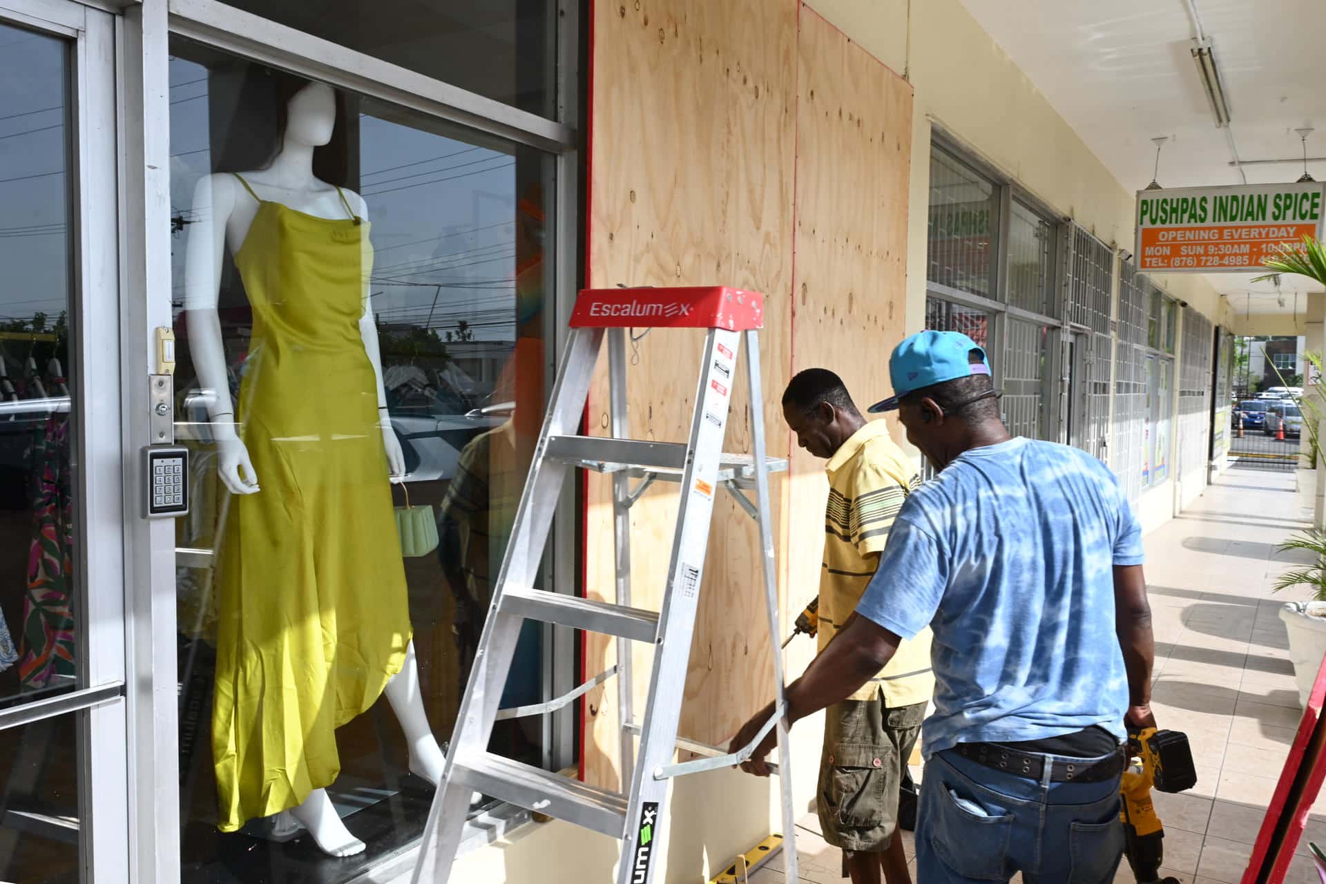 Personas cubren las fachadas de los negocios con tablones de madera ante la inminente llegada del huracán Beryl ayer martes en Kingston (Jamaica). EFE/ Rudolph Brown