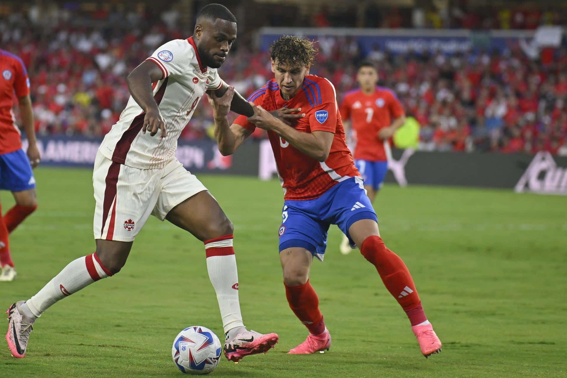 El delantero canadiense Cyle Larin (i) fue registrado este sábado, 29 de junio, al disputar un balón con el defensa chileno Igor Lichnovsky (c), durante el partido de cierre del grupo A de la Copa América 2024, en el estadio Inter&Co de Orlando (Florida, EE.UU.) EFE/Miguel Rodríguez