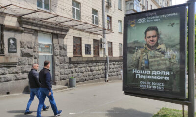 Dos hombres ucranianos pasan por delante de un anuncio de una unidad del ejército el pasado 16 de mayo en Kiev. EFE/ Marcel Gascón