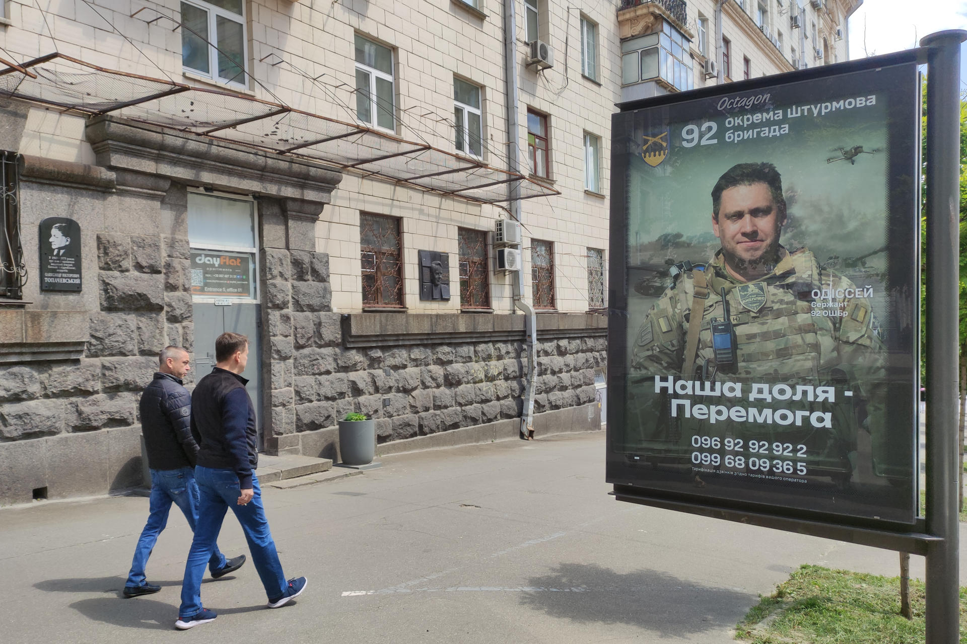 Dos hombres ucranianos pasan por delante de un anuncio de una unidad del ejército el pasado 16 de mayo en Kiev. EFE/ Marcel Gascón
