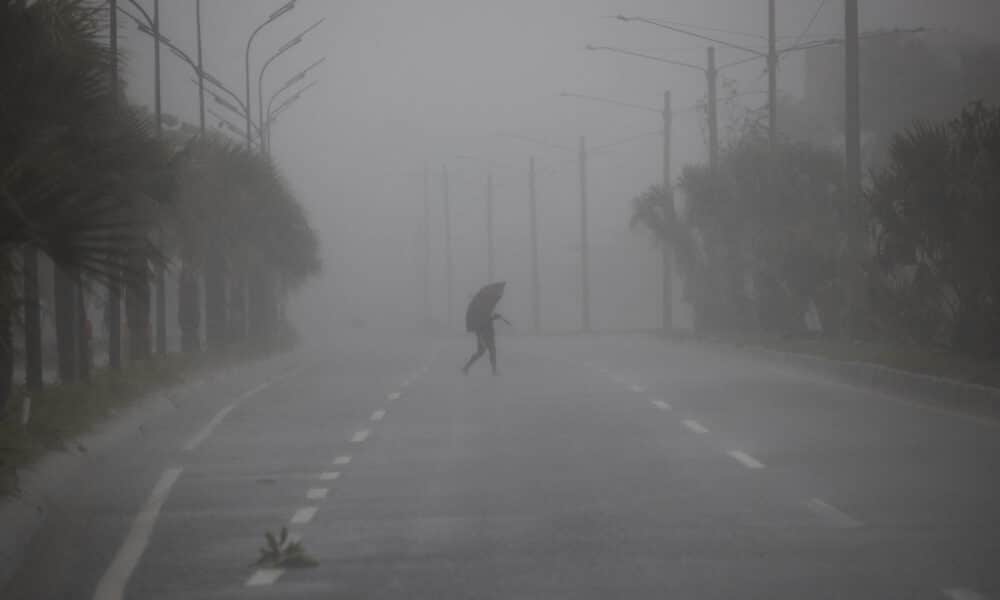 Una persona cruza hoy una avenida bajo una fuerte lluvia debido al paso de una tormenta tropical en Santo Domingo (República Dominicana). Fotografía de archivo. EFE/Orlando Barría