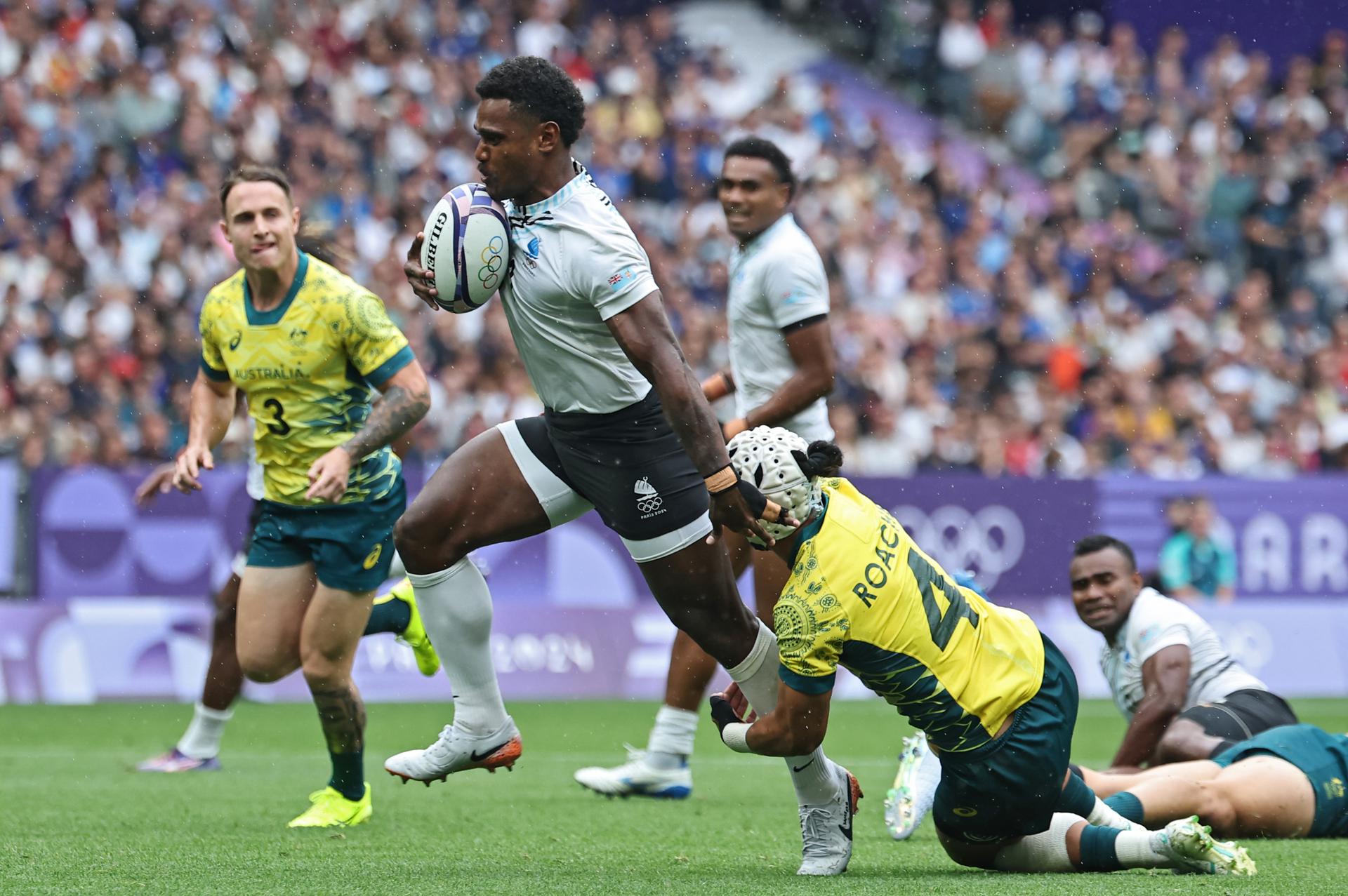 El jugador Jerry Tuwai, de Fiji, deja a trás al australiano durante el partido de semifinales que han jugado Fiji y Australia en el Stade de France en Saint Denis, Francia. EFE/EPA/CHRISTOPHE PETIT TESSON