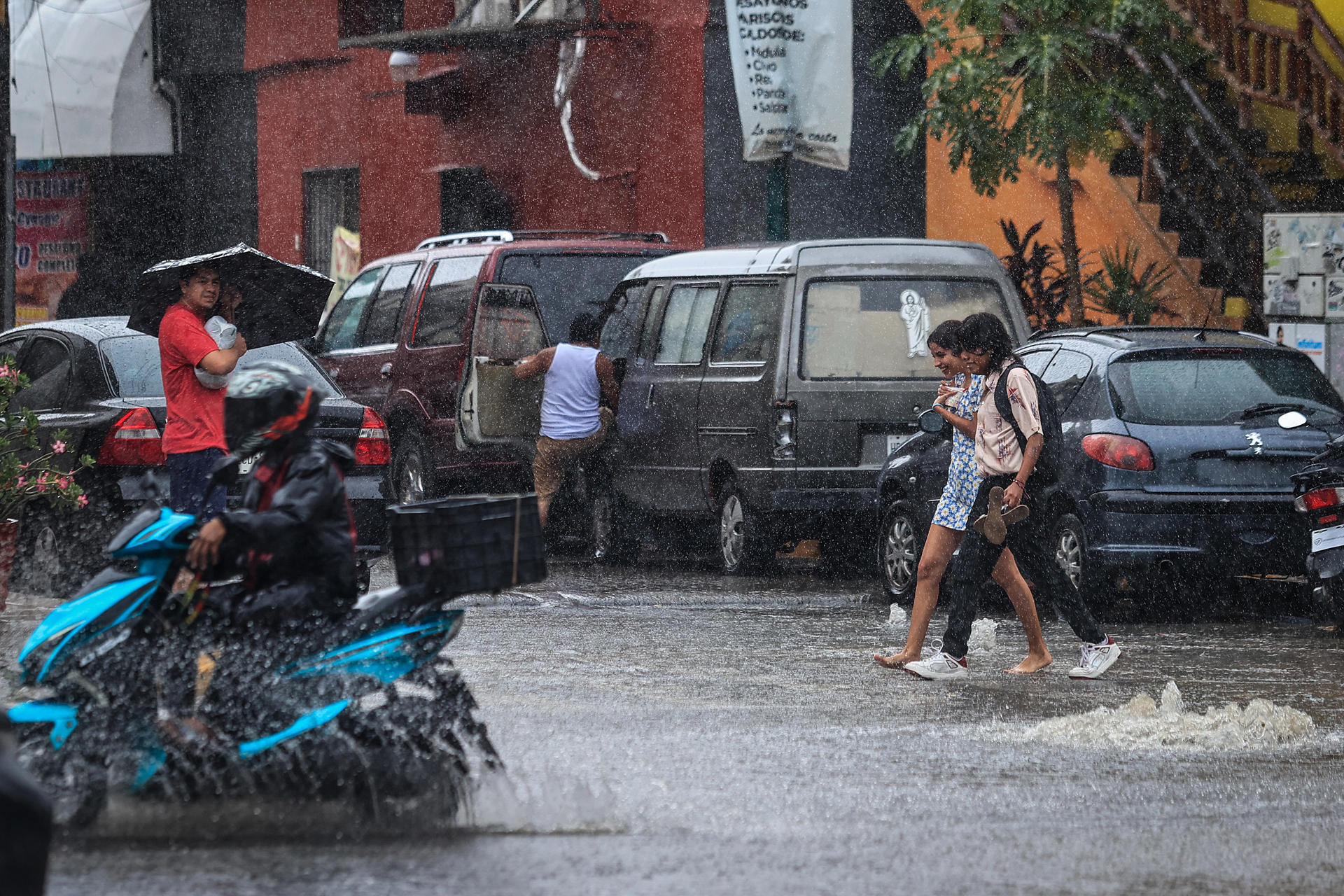 Imagen de archivo de personas que caminan por una calle encharcada debido a las fuertes lluvias en Guadalajara, Jalisco. EFE/David Guzmán