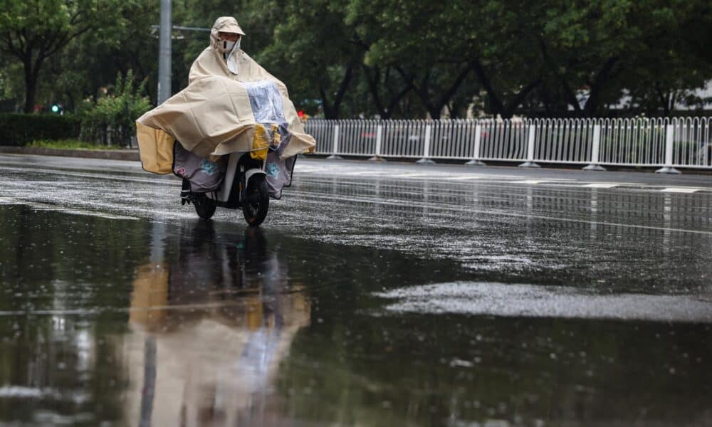 Una mujer anda en scooter durante una fuerte lluvia, en una calle de Beijing (China), el 30 de julio de 2024. El Observatorio Meteorológico Central siguió emitiendo una alerta naranja por tormenta para el martes. EFE/EPA/Wu Hao