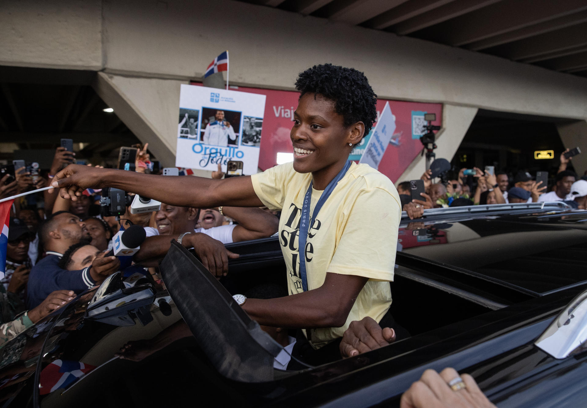 Marileidy Paulino, ganadora de la medalla de oro en los 400 metros en los Juegos Olímpicos de París 2024, saluda durante su recibimiento en el Aeropuerto Internacional de las Américas, en Santo Domingo (República Dominicana). EFE/Orlando Barría