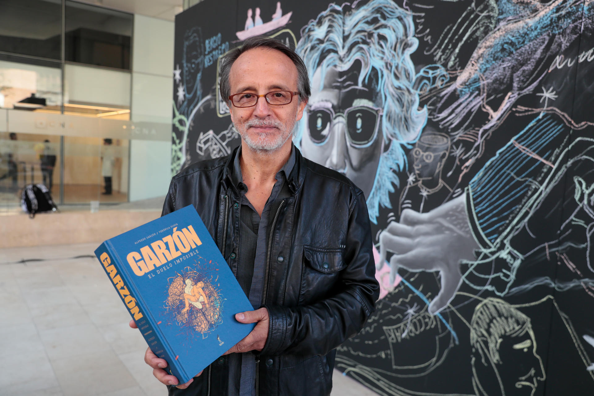 El caricaturista Alfredo Garzón, hermano del periodista y humorista asesinado Jaime Garzón, posa con el libro 'Garzón El duelo imposible' vendido este martes 13 de agosato de 2024 durante un acto conmemorativo en Bogotá (Colombia). EFE/Carlos Ortega