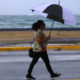 Una mujer se protege de la lluvia con una sombrilla frente a la Playa de Ocean Park, en San Juan (Puerto Rico). EFE/ Thais Llorca