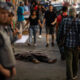 Fotografía de archivo en donde se ve a una persona sin hogar mientras duerme entre compradores y policías en São Paulo (Brasil). EFE/ Isaac Fontana