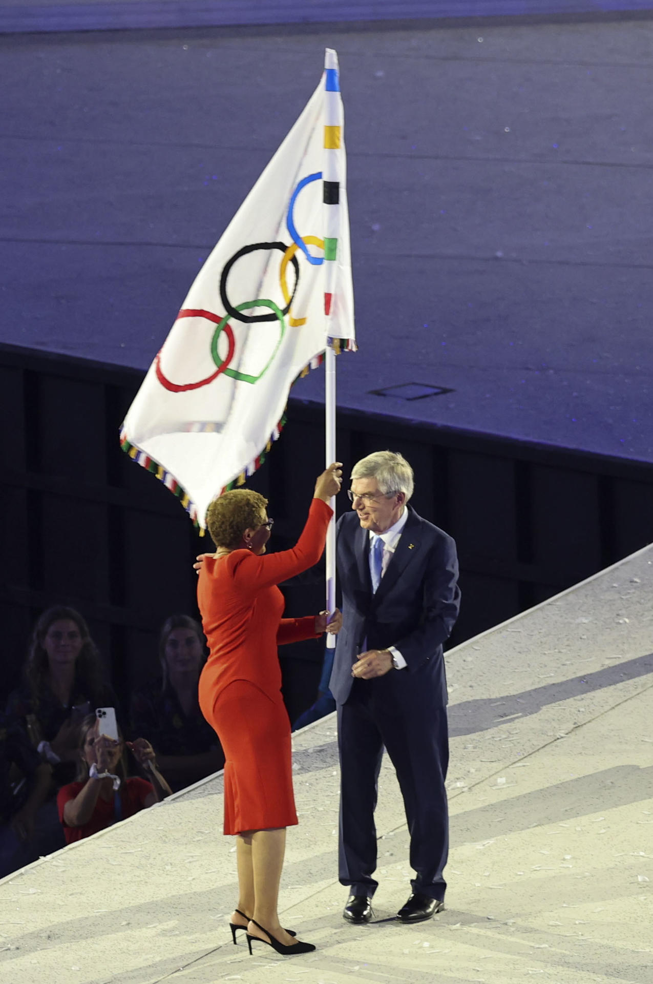 La alcaldesa de Los Angeles, Karen Bass (i), con la bandera olímpica, junto al presidente del COI, Thomas Bach, durante la ceremonia de clausura de los Juegos Olímpicos de París 2024 celebrada en el Estadio de Francia en Saint-Denis (Francia).EFE/ Miguel Gutiérrez