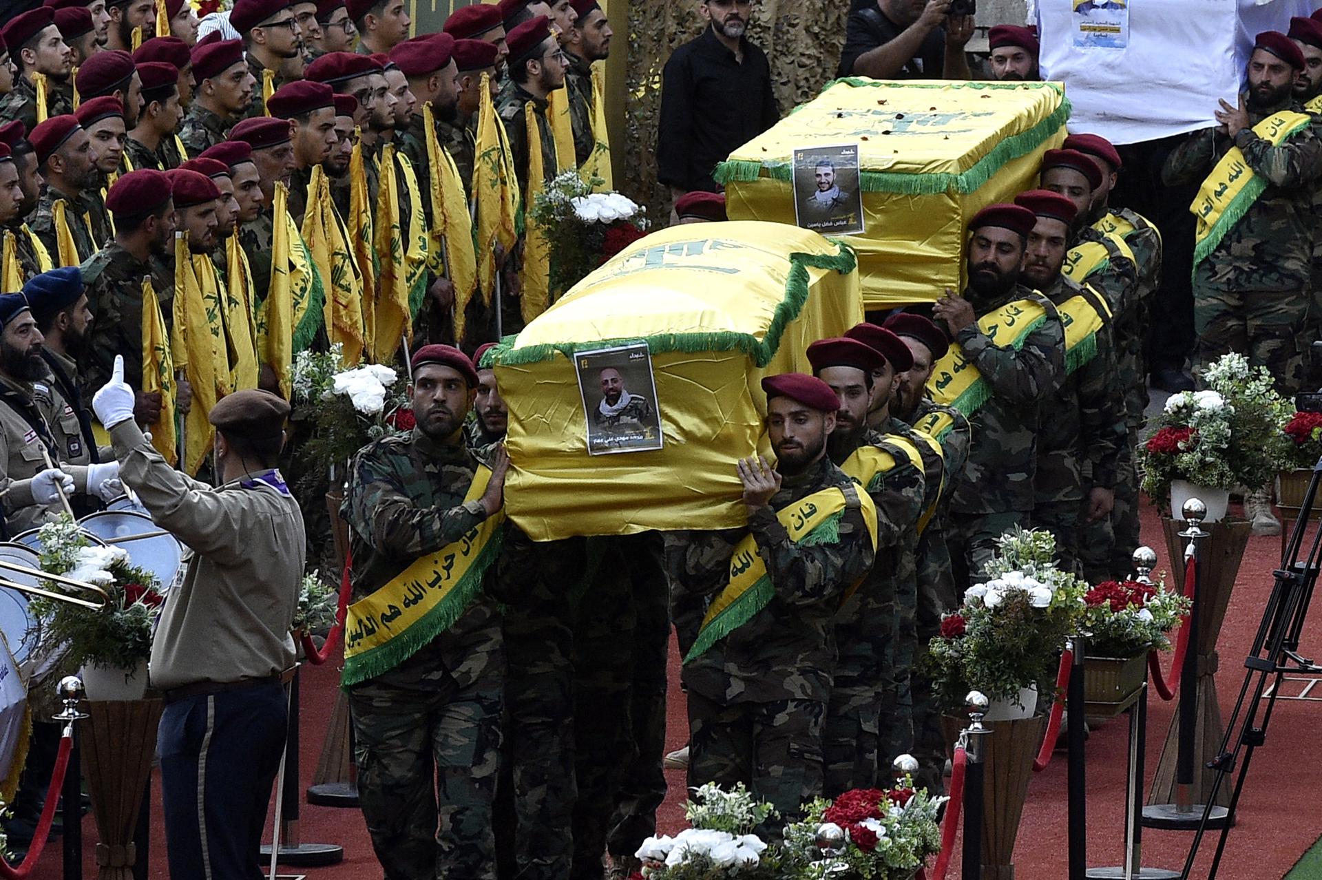 Combatientes de Hezbolá llevan los ataúdes de cuatro personas que murieron un día antes en explosiones de buscapersonas, durante una procesión fúnebre en el suburbio sur de Beirut, Líbano, el 18 de septiembre de 2024. El ministro de Salud del Líbano, Firas Abiad, dijo que al menos 12 personas murieron y más de 2.800 resultaron heridas después de que varios dispositivos de comunicación inalámbrica (buscapersonas) fueran detonados el 17 de septiembre. Hezbolá declaró en un comunicado que Israel estaba detrás del ataque y que habrá consecuencias. (Líbano, Hizbulá/Hezbolá) EFE/EPA/WAEL HAMZEH