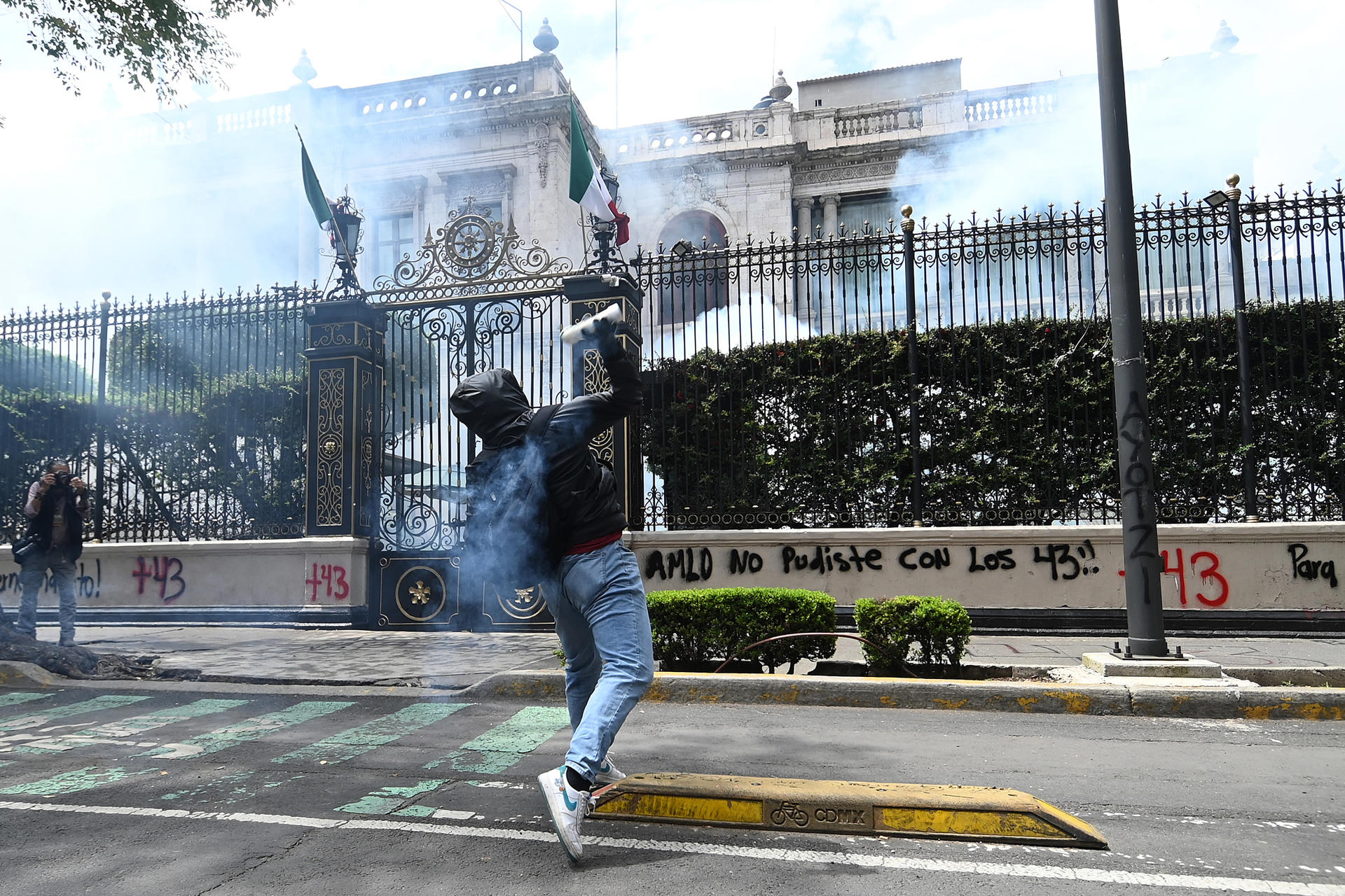 Un manifestante lanza un explosivo a la sede de la Secretaría de Gobernación (Segob) este lunes, en la Ciudad de México (México). EFE/ Madla Hartz