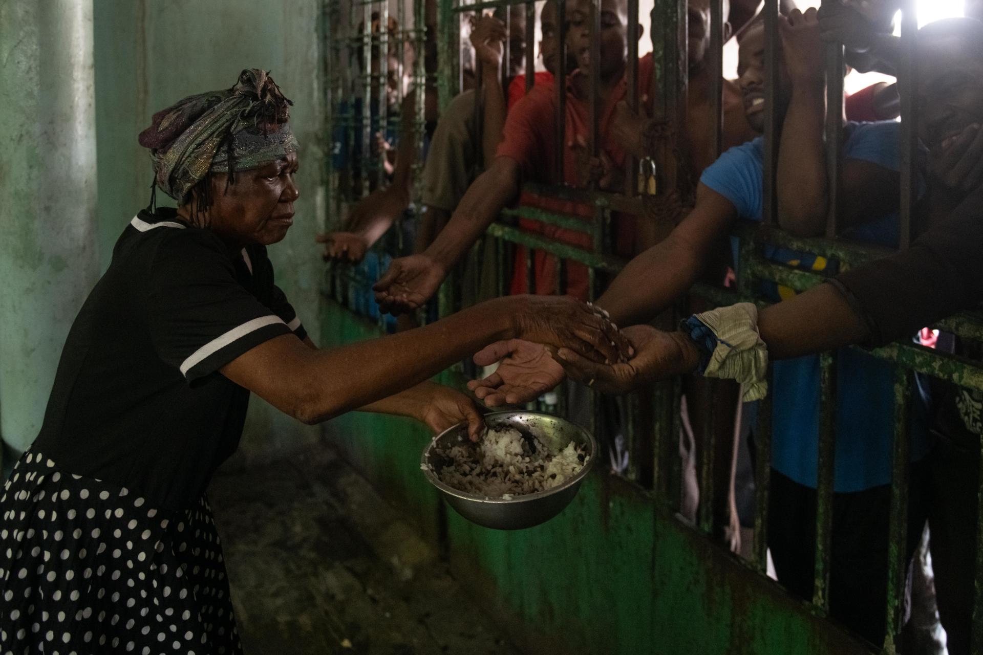 Una mujer da comida a hombres en el centro psiquiátrico Mars & Kline en el centro de Puerto Príncipe (Haití). Fotografía de archivo. EFE/ Johnson Sabin