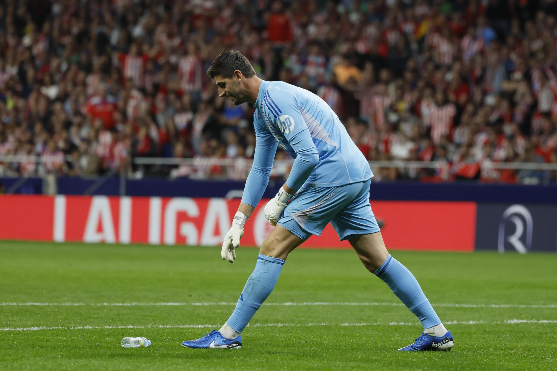 El portero del Real Madrid Thibaut Courtois retira un objeto lanzado desde la grada, durante el partido de la LaLiga EA Sports que Atlético de Madrid y Real Madrid disputaron en el estadio Civitas Metropolitano. EFE/Ballesteros