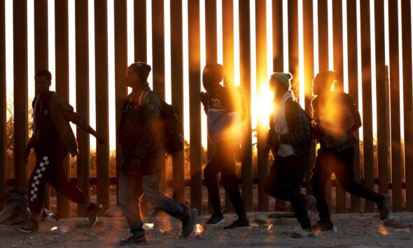 Fotografía de archivo de migrantes que caminan junto al muro en la frontera de EE.UU, y México en Lukeville, Arizona, EE.UU. EFE/ Allison Dinner