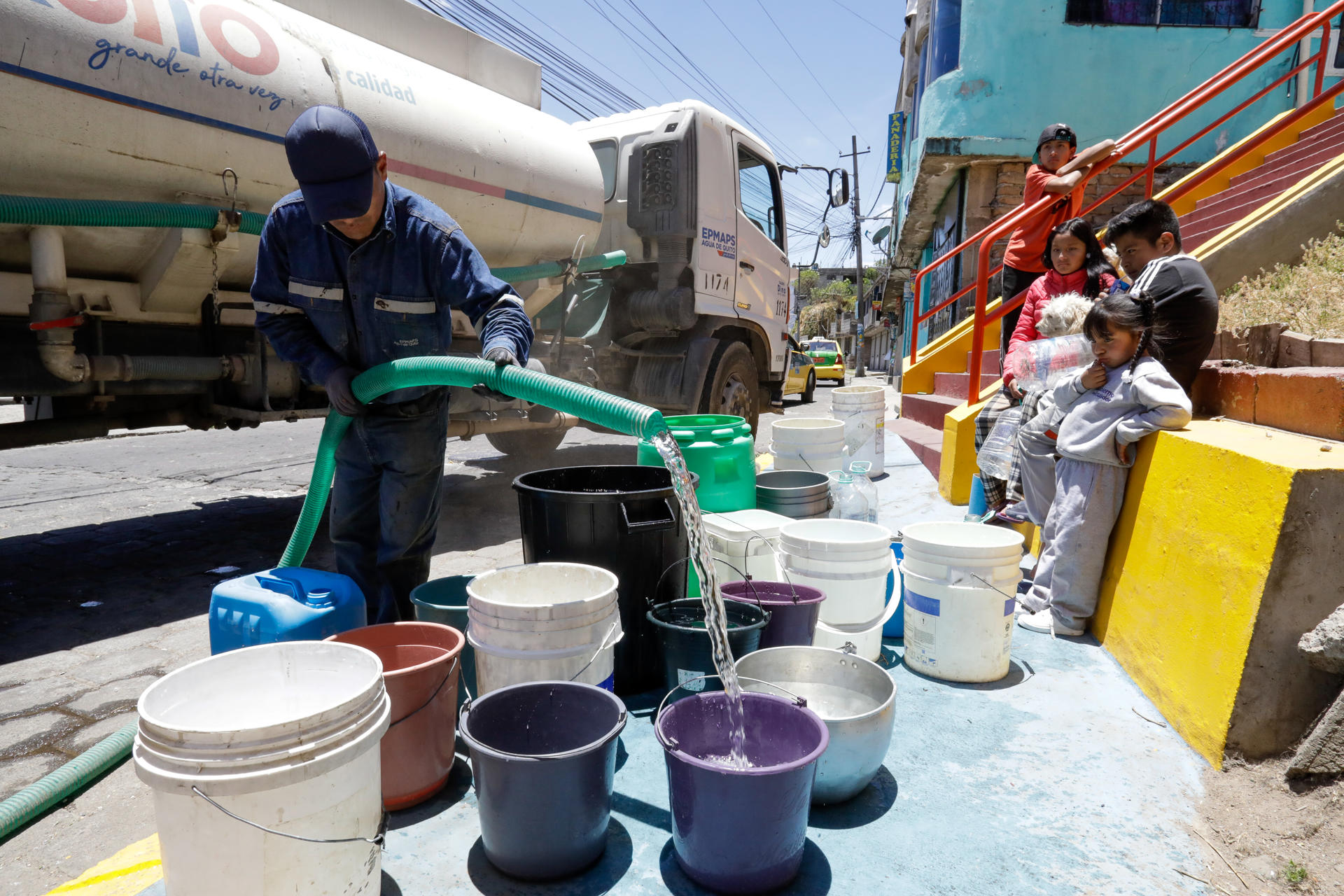 Un hombre llena unos recipientes con agua este martes en el barrio La Forestal, en Quito (Ecuador). EFE/José Jácome