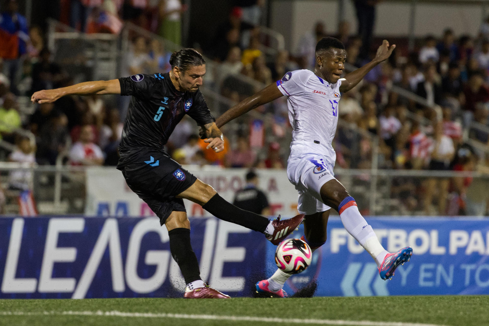 Zarek Valentin (i) de Puerto Rico disputa el balón con Jean Denley de Haití en un partido de la Liga de Naciones de la Concacaf, en el estadio José Antonio Figueroa en Mayagüez (Puerto Rico). EFE/ Thais Llorca